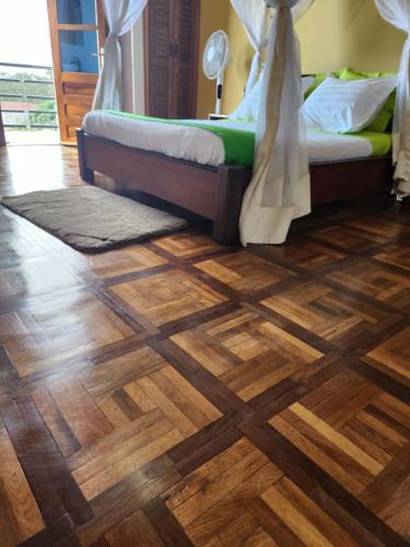 a room with a bed and a wooden floor at MANGORO HOTEl in Moramanga