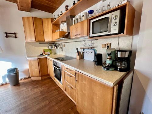 a small kitchen with wooden cabinets and a microwave at Holiday Home Celine in Velké Svatoňovice