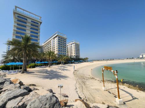 a beach with buildings and palm trees and the ocean at Marjan Island Beautiful Apartment Sea View Beach Luxury Rooms Ras Al Khaimah UAE in Ras al Khaimah