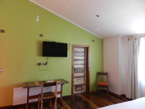 1 dormitorio con una pared verde, escritorio y TV en Aroma Verde Hotel, en Valdivia
