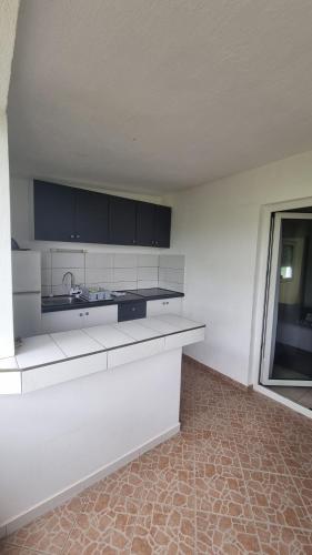 an empty kitchen with white counters and a window at Apartments Šešo in Pag