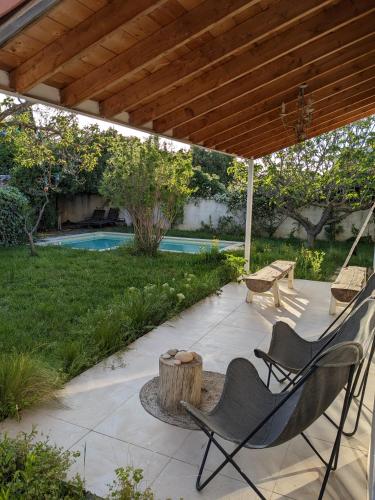 un patio sous une pergola en bois avec un banc et une table dans l'établissement Villa 10 Pers Piscine proche Plage Carnon, à Pérols