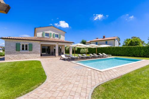 a villa with a swimming pool in front of a house at Villa Dionis in Kaštelir