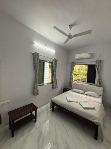 - une chambre avec un lit et un ventilateur de plafond dans l'établissement White Haven Homestay, à Alībāg