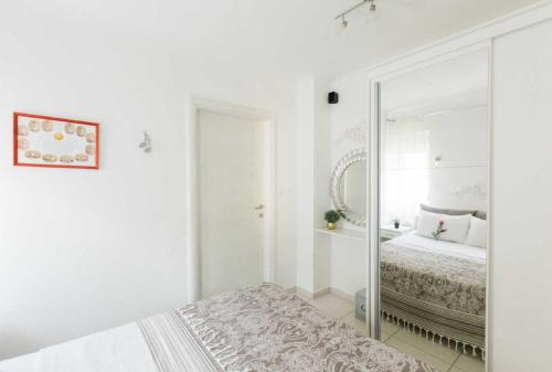 a white bedroom with a mirror and a bed at Mahakala Center in Petrovac na Moru