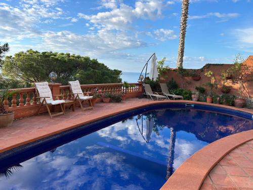 ein Swimmingpool mit zwei Stühlen und einem Tisch in der Unterkunft Villa Caprice in Lloret de Mar