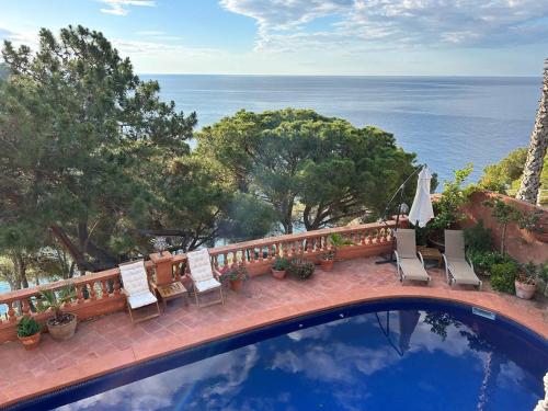 einen Pool mit Stühlen und Meerblick in der Unterkunft Villa Caprice in Lloret de Mar