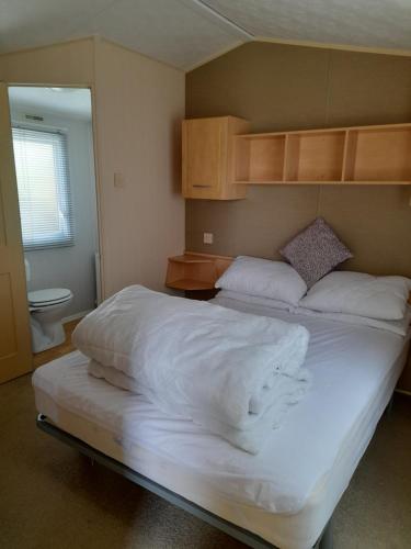 a bedroom with a large bed with white sheets at Blancos by the sea in Saint Osyth