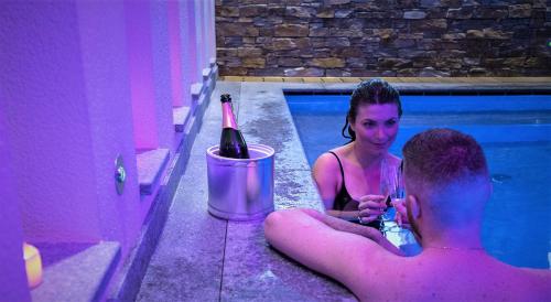 een man en een vrouw in een zwembad met een fles wijn bij Residence Hotel Miralago in Pergine Valsugana