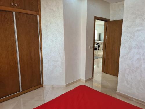 a living room with a red rug and wooden cabinets at Appartements Horizon in M'diq