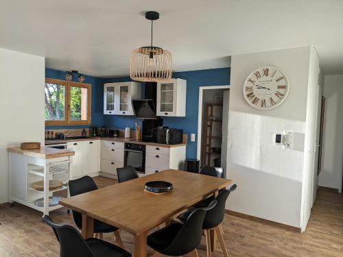 une cuisine avec une table et une horloge au mur dans l'établissement Jolie maison landaise tout confort, à Lugos