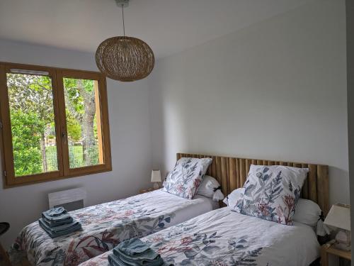 une chambre avec deux lits et une fenêtre dans l'établissement Jolie maison landaise tout confort, à Lugos