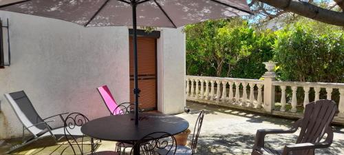 stół i krzesła z parasolem na patio w obiekcie Charmant appartement de vacances w Argelès-sur-Mer