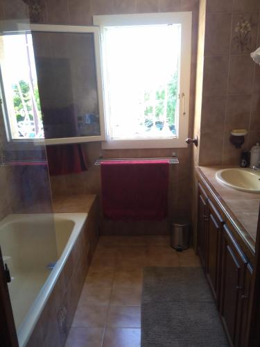 une salle de bain avec une baignoire, un lavabo et une fenêtre dans l'établissement villa spacieuse avec piscine, à La Crau