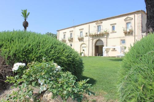 a villa with a palm tree in front of a building at Castello Camemi in Vizzini