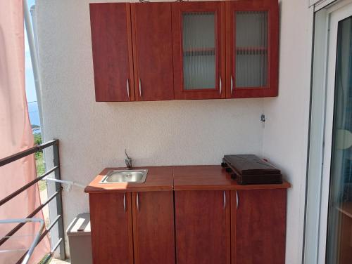 uma cozinha com um lavatório e armários de madeira em Apartment Lia em Masline