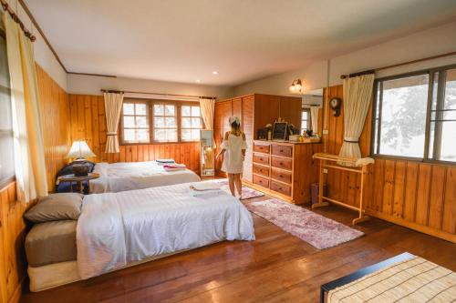 a woman standing in a bedroom with two beds at Ban MaeBo Local Stay in Ban Nong Han