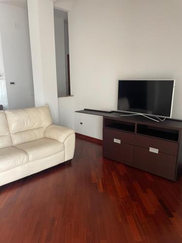 salon z białą kanapą i telewizorem z płaskim ekranem w obiekcie Heaven's Door w mieście San Giovanni Rotondo
