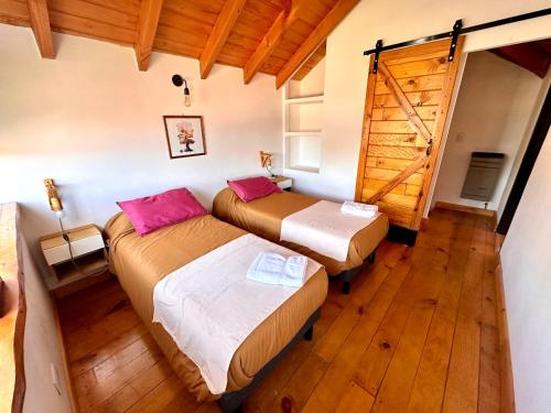 two beds in a room with wooden floors at Las Araucarias Caviahue in Caviahue