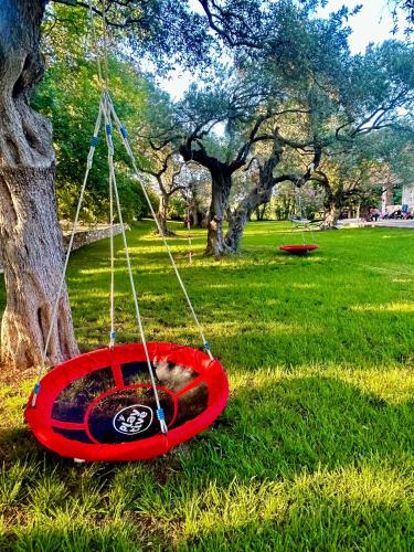 a cat sleeping in a red bowl in front of a tree at Natura Bungalows-Villa in Limenas