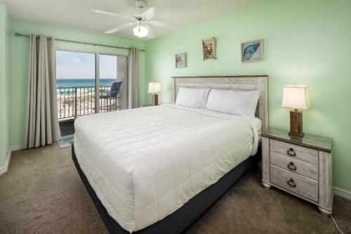 een slaapkamer met een bed en een balkon met uitzicht op de oceaan bij Gulf Dunes 208: Beautifully remodeled condo, fee beach chairs, tennis court in Fort Walton Beach