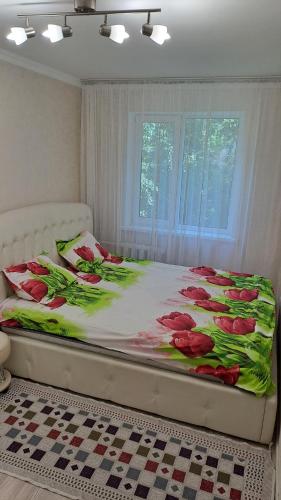 a bed with red flowers on it in a bedroom at MargoHome in Almaty