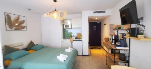 Cet appartement comprend une chambre avec un lit vert et une cuisine. dans l'établissement O'TINY Suite familiale 4 personnes, gare, centre ville, sanctuaire, à Lourdes