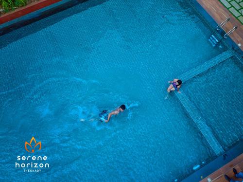 two people are swimming in a swimming pool at Serene Horizon in Thekkady