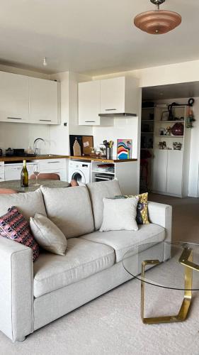 un salon avec un canapé et une cuisine dans l'établissement Appartement Cosy Pantin, à Pantin