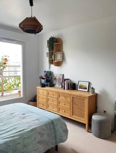 une chambre avec un lit et une commode en bois dans l'établissement Appartement Cosy Pantin, à Pantin