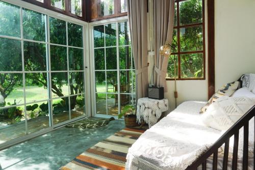 a bedroom with a bed and large windows at Suksamer Relaxation Homestay 