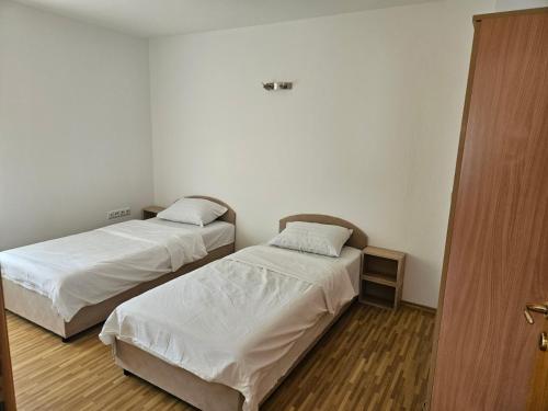 two beds in a room with a door open at Apartman Rakovica in Sarajevo