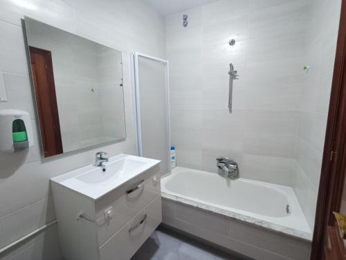 a white bathroom with a sink and a bath tub at A Barca de Pedra in Padrón