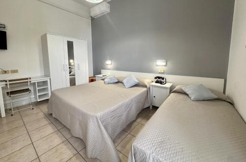 um quarto com 2 camas, uma mesa e um espelho em Hotel Amelia em Fano