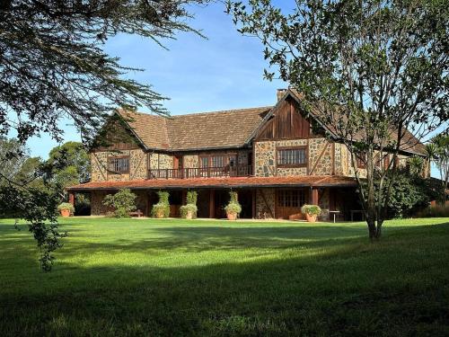 a large wooden house with a green lawn at Mukima Manor in Nanyuki