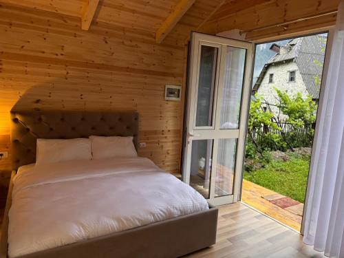 a bed in a wooden room with a large window at Thethi Mountain Villas in Theth