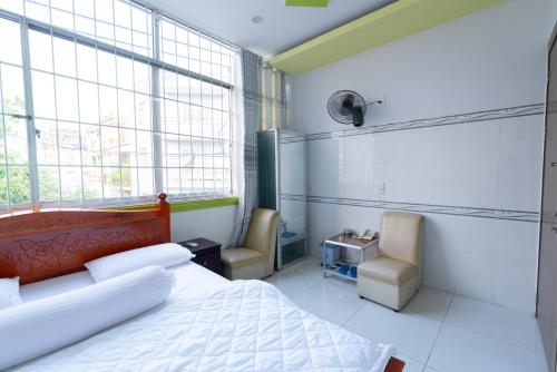 a bedroom with a bed and two chairs and a window at Thien Thanh Hotel in Vĩnh Long