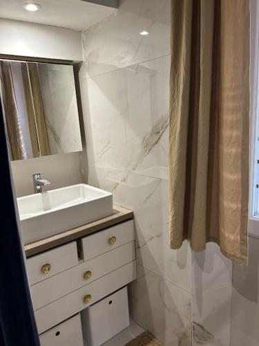 une salle de bain blanche avec un lavabo et un miroir dans l'établissement Résidence Cannes Plage Business Saisonnier, à Cannes