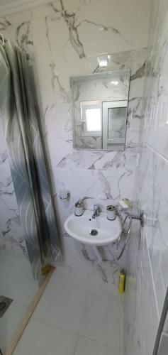 Cozzy apartment near the Aiport Podgorica في Mitrovići: حمام أبيض مع حوض ومرآة