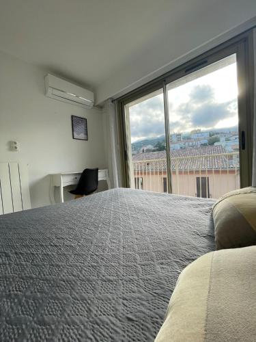 une chambre avec un grand lit et une grande fenêtre dans l'établissement VOLTA, à Bastia