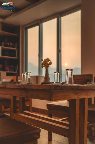 a wooden table with glasses and a vase on it at Thumki Resort, Balthali in Panauti