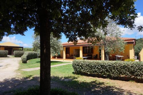 a yellow house with a tree and bushes at Rosanna House in Bombarde Beach in Alghero