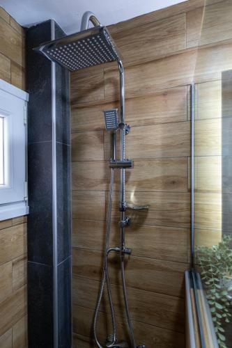 a shower in a bathroom with a wooden wall at Antigone View Apartments in Skala Potamias