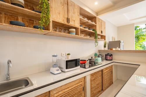 a kitchen with wooden cabinets and a microwave at ☆ Villa Larissa ☆ Seminyak 2BR Pool Kuta Petitenget in Seminyak