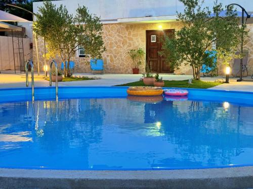 einen Pool mit blauem Wasser vor einem Haus in der Unterkunft Apartments Villa Mihaela in Banj