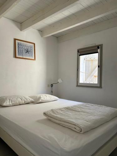 un lit dans une chambre blanche avec une fenêtre dans l'établissement Mooie plek direct aan het strand in Zuid Frankrijk, au Cap d'Agde