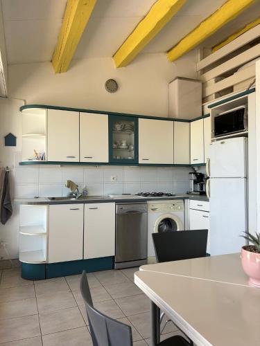 une cuisine avec des armoires blanches et une table avec des chaises dans l'établissement Mooie plek direct aan het strand in Zuid Frankrijk, au Cap d'Agde