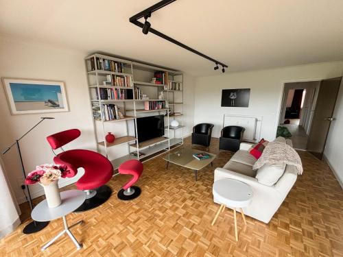 a living room with a white couch and red chairs at Large sunny and bright apartment with park view in Ostend