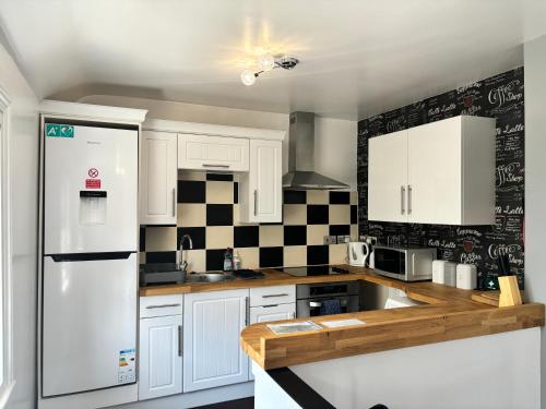 een keuken met witte kasten en een witte koelkast bij Royal Manor Park in Llandudno