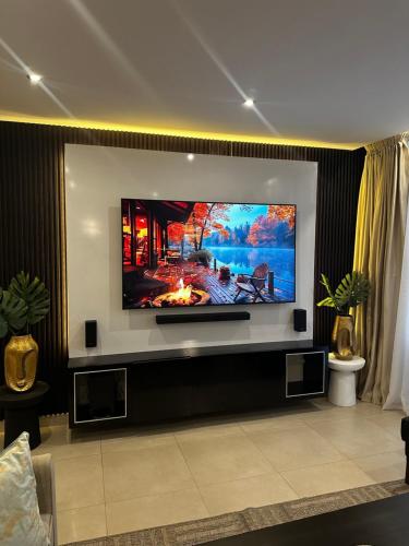 TV de pantalla plana en la pared de la sala de estar. en GreenHome 75 inch TV 5mints from the beach and City, en Dar es Salaam